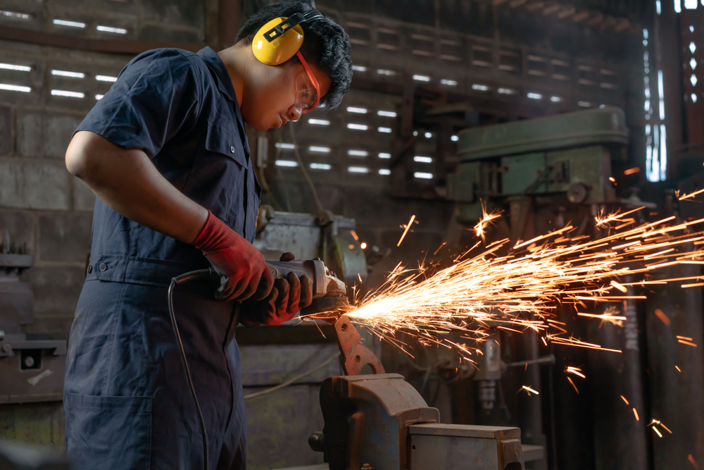 Engineer operating angle grinder hand tools in manufacturing factory